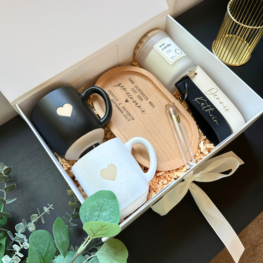Personalisiertes Geschenkset zur Hochzeit – weiße Box mit Tassen, Tablett, Kerze und Schlüsselanhängern mit Namen und Datum.