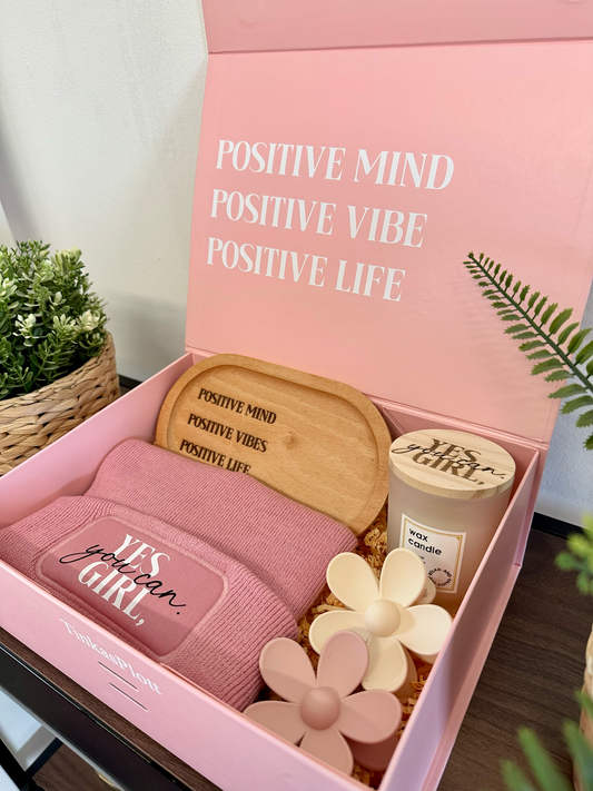 Detailaufnahme der Geschenkbox-Inhalte: motivierende Mütze, duftende Kerze im Glas, dekorative Haarklammern und Holztablett mit Gravur. Geschenkidee für Frauen mit Liebe verpackt – auf dem Innendeckel steht der Spruch „Positive Mind Positive Vibe Positive Life“.
