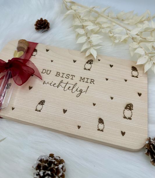 Kleines Frühstücksbrett mit Gravur „Weil du mir wichtelig bist“, liebevoll verpackt mit Schleife und Reagenzglas – perfekt als Weihnachtsgeschenk oder Wichtelgeschenk. Holzbrett mit Lasergravur, handgefertigt, dekorativ und ideal für Geldgeschenke zu Weihnachten.